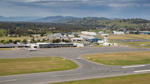 Aerial picture of airport team on tarmac with reporting officer ute, plane and terminal in background